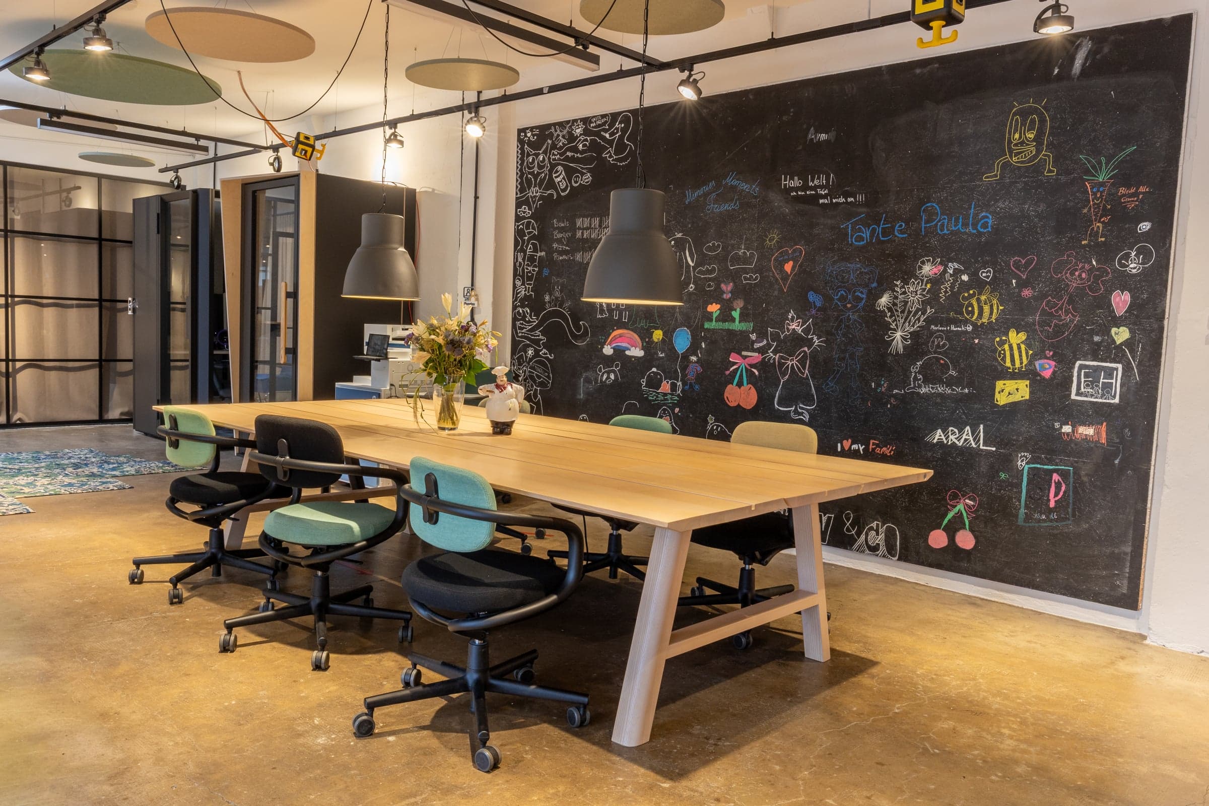 Open meeting area with a large table and a wall covered in writing